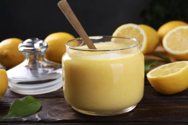 Cam kavanozda lezzetli limon ezmesi taze narenciye meyvesi ve ahşap masada kaşık.