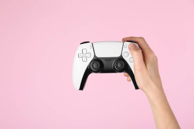 Pembe arka planda oyun kontrolörü olan kadın, yakın plan