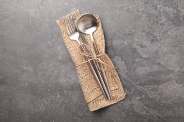 Gri desenli masa üzerinde şık çatal bıçak seti ve peçete.