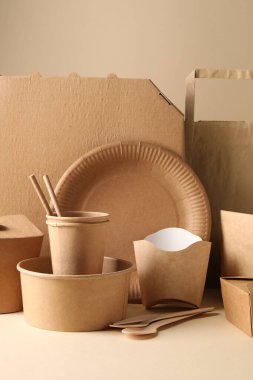 Çevre dostu gıda ambalajı. Kağıt kaplar, sofra takımı ve çanta bej arka plana karşı beyaz masa üzerinde