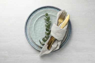 Çatal bıçak takımı, peçete, okaliptüs dalı ve tabaklar beyaz masa, üst görünüm