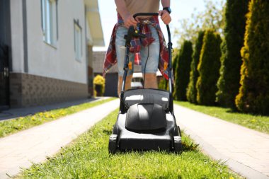 Bahçede çim biçme makinesiyle çimen biçen adam, yakın plan.