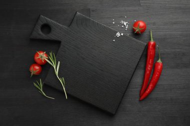 Kesme tahtası, biberiye, biber biberi ve domatesler siyah ahşap masa, düz yatak. Metin için boşluk