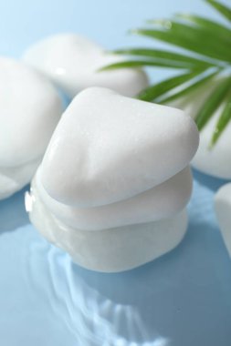 Açık mavi arkaplanda suda spa taşları, yakın plan