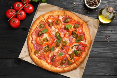 Lezzetli pizza Diablo ve siyah ahşap masa üzerindeki malzemeler, düz yatıyordu.