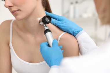 Dermatoskoplu bir dermatolog klinikteki hastayı muayene ediyor.