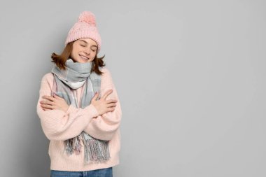 Sıcak atkı ve gri arka planda şapka takan güzel kadın, metin için yer var.