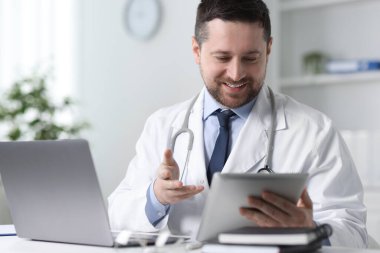 Gülümseyen doktor, klinikteki masada tabletle online danışmanlık yapıyor.