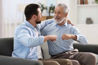 Mutlu oğul ve babası evde yumruk tokuşturuyorlar.