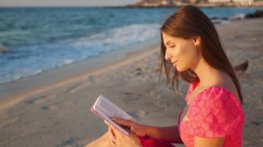 Sabahları sahilde kitap okuyan güzel bir kadın. Kamera hareket ediyor kızım.