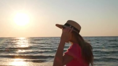 Denize yürüyen şapkalı güzel bir kadın. Kamera kızdan sonra hareket ediyor