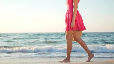 Sabahları sahilde çıplak ayakla yürüyen bir kadın, yakın plan. Kamera kızla hareket ediyor