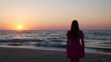 Gün batımında denizin tadını çıkaran bir kadın.