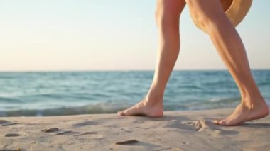 Güneşli bir sabahta çıplak ayakla denizde yürüyen bir kadın. Yakın plan. Kamera kızdan sonra hareket ediyor