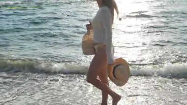 Sahilde çıplak ayakla yürüyen güzel bir kadın. Kamera sola hareket ediyor