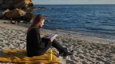 Deniz kenarında kitap okuyan güzel bir kadın.