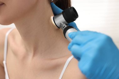 Dermatoskoplu bir dermatolog klinikteki hastayı muayene ediyor.