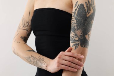 Hafif arka planda havalı dövmeleri olan kadın, yakın plan.