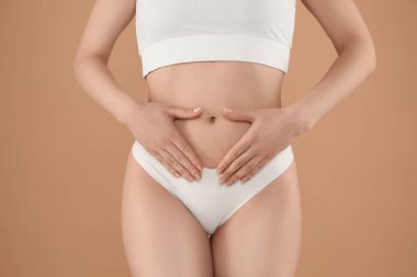 Gynecology. Woman in underwear on beige background, closeup