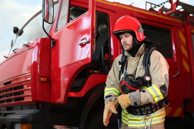 Firefighter in uniform near red fire truck at station