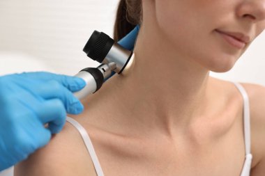 Dermatoskoplu bir dermatolog klinikteki hastayı muayene ediyor.