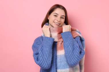 Beautiful woman in warm scarf on pink background