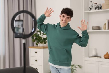 Smiling teenage blogger dancing while streaming at home