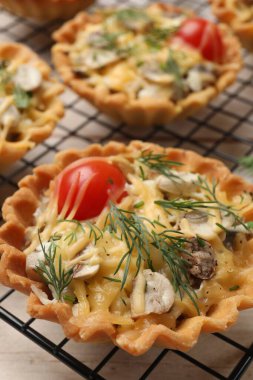 Tasty tartlets with cheese, tomatoes, mushrooms and dill on table, closeup