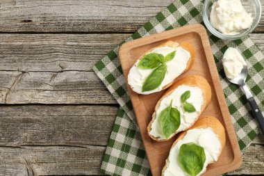 Tahta masada krem peynirli ve fesleğen yapraklı lezzetli sandviçler. Metin için boşluk