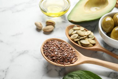 Farklı tohumlar ve ürünler beyaz mermer masa üzerinde sağlıklı yağlarda, yakın plan. Metin için boşluk