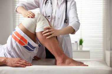Spor sakatlığı. Hastanede hastanın dizini muayene eden doktor, yakın plan.