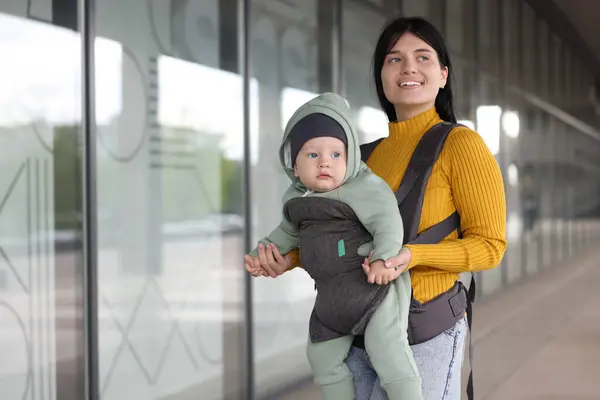 stock image Mother holding her child in sling (baby carrier) near building outdoors