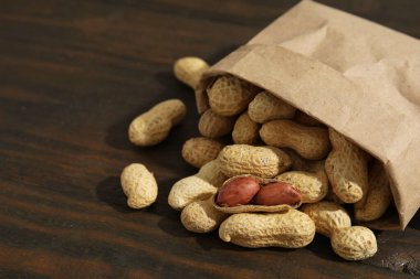 Tahta masanın üzerinde taze fıstıklı kağıt torba, yakın plan. Metin için boşluk