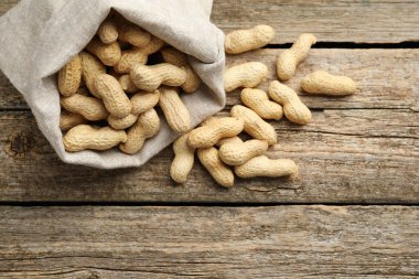 Ahşap masada, görüntünün üstünde, kabuğu soyulmamış fıstıklar var. Metin için boşluk