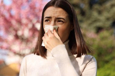 Woman with napkin suffering from seasonal allergy on spring day