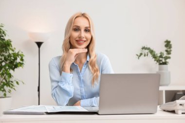 Masada dizüstü bilgisayarlı mutlu bir sekreter.