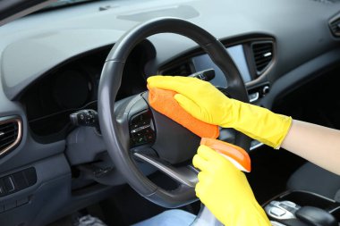 Arabasında bez parçasıyla direksiyonu temizleyen kadın, yakın plan.