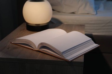 Gece lambası ve kitap yatağın yanındaki komodinin üzerinde.