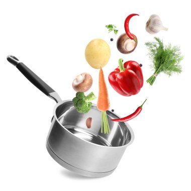 Beyaz arkaplanda tencereye düşen taze malzemeler