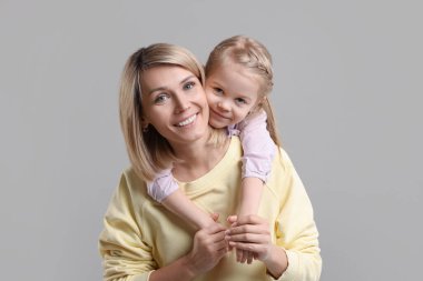 Family portrait of happy mother and daughter on grey background