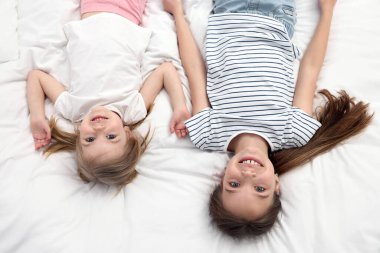 Yatakta sevimli küçük kız kardeşler, üst manzara.