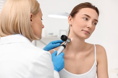 Dermatoskoplu bir dermatolog klinikteki hastayı muayene ediyor.