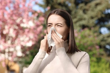 Woman with napkin suffering from seasonal allergy on spring day