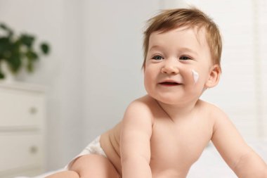 Yüzünde nemlendirici krem olan şirin bir bebek.