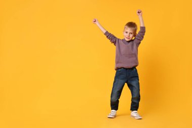 Sarı arka planda dans eden mutlu küçük çocuk. Metin için boşluk