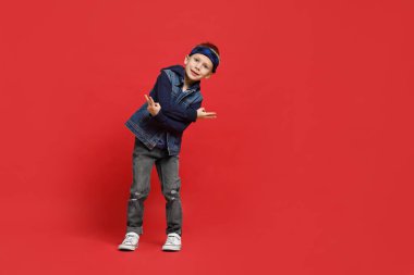 Kırmızı arka planda dans eden mutlu küçük çocuk. Metin için boşluk