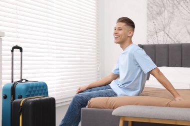 Gülümseyen misafir şık bir otel odasında yatakta dinleniyor.