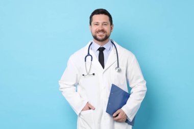 Smiling doctor with clipboard on light blue background
