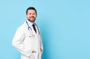 Açık mavi arka planda steteskobu olan gülümseyen bir doktor. Metin için boşluk