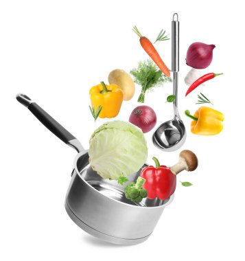 Beyaz arkaplanda tencereye düşen taze malzemeler